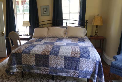king bed with blue quilt, french windows