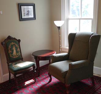 corner sitting area with 2 chairs, window, lamp, painting, rug